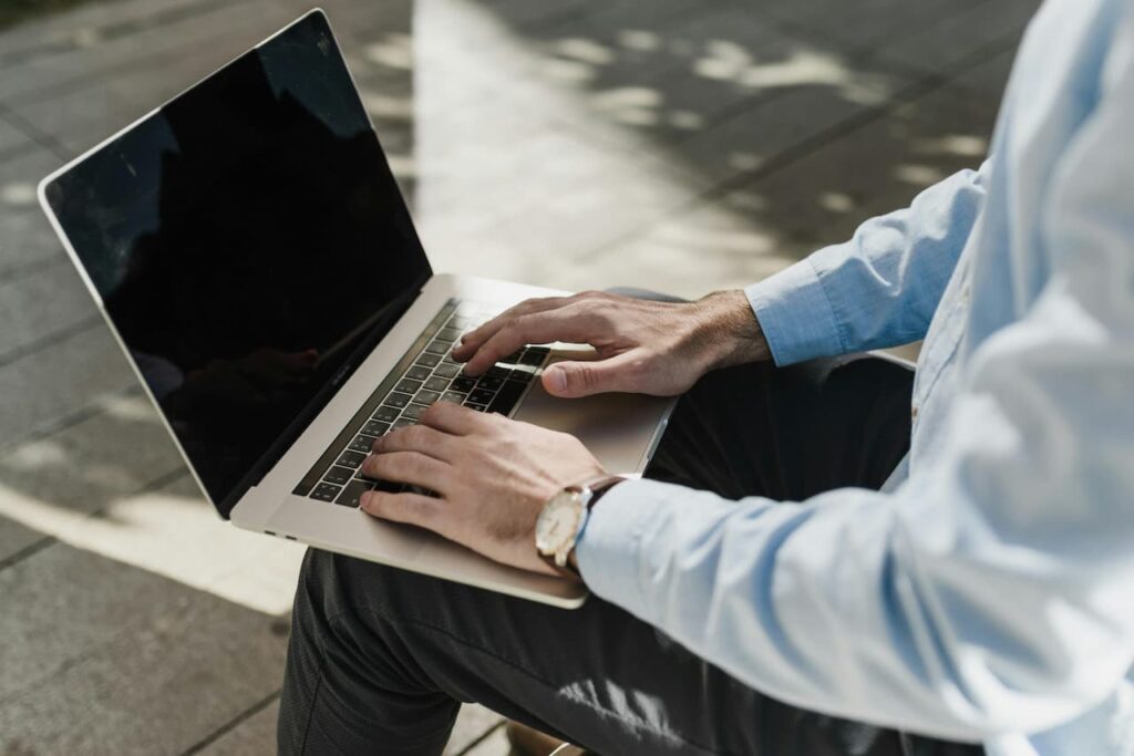 Utilisateur travaillant sur un MacBook en extérieur, illustrant les astuces pour économiser la batterie et prolonger l’autonomie d’un Mac.