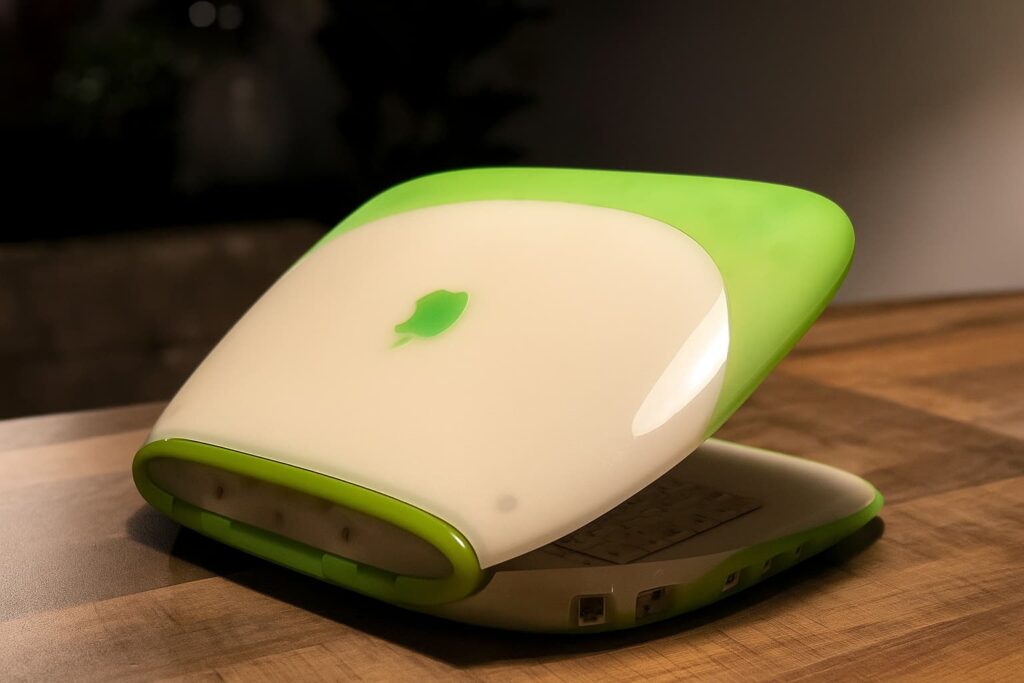 iBook G3 coquillage vert partiellement ouvert sur une table en bois, ancien ordinateur portable Apple à recycler ou réutiliser.
