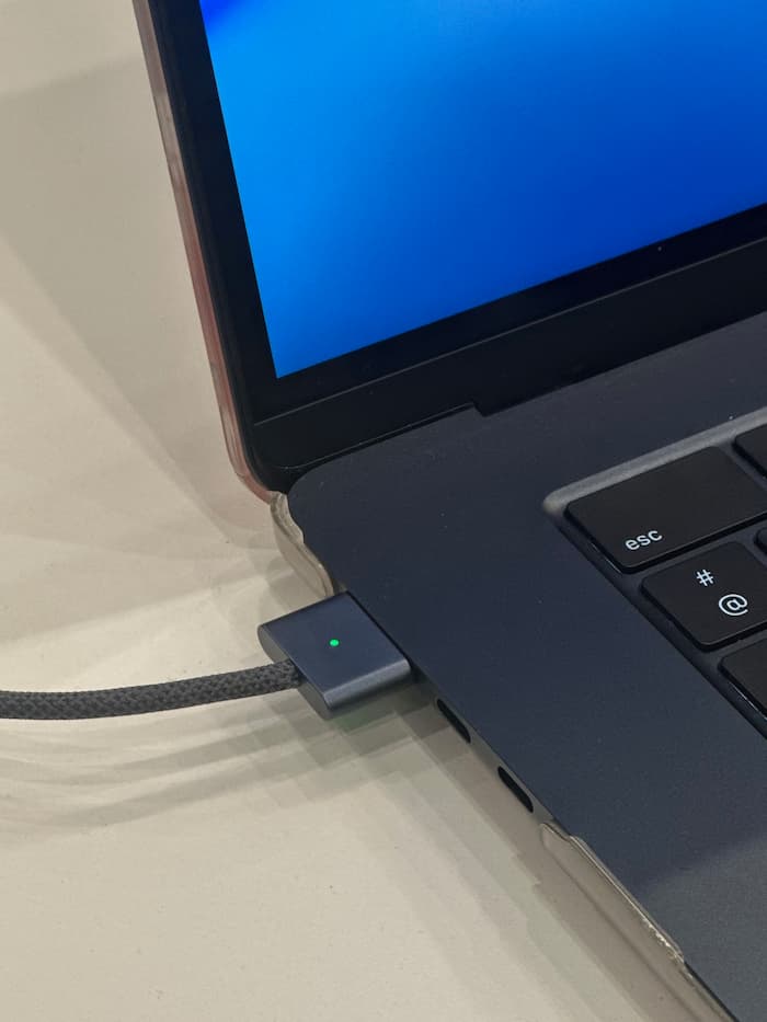 Connecteur de charge MagSafe branché sur un MacBook Apple avec voyant vert