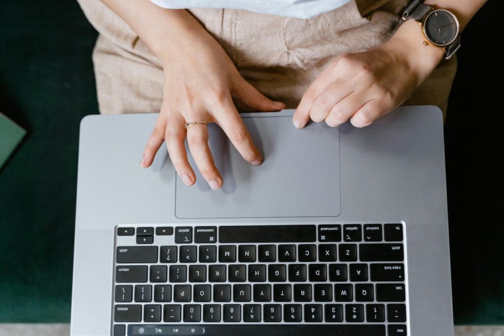 Vue de dessus des mains d'une personne utilisant un trackpad de MacBook Pro parfaitement fonctionnel après une réparation.