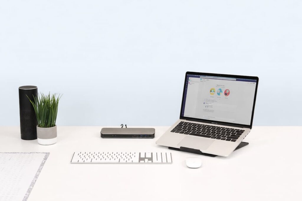 MacBook ouvert sur un bureau blanc avec clavier Magic Keyboard et Magic Mouse Bluetooth Apple
