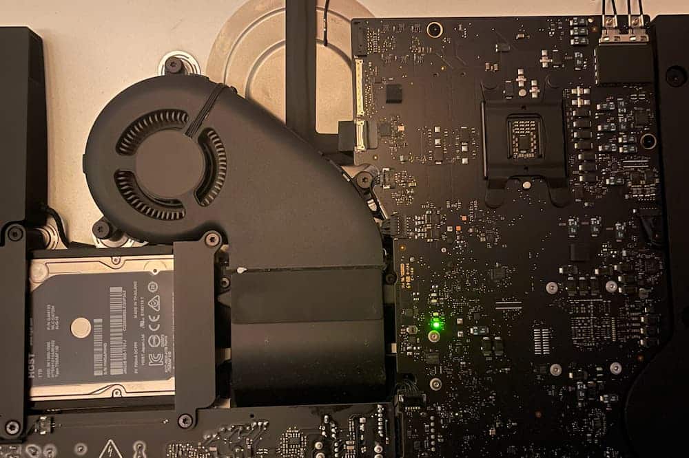 Vue interne iMac avec carte mère et LED de diagnostic allumée indiquant une panne ou un test au démarrage