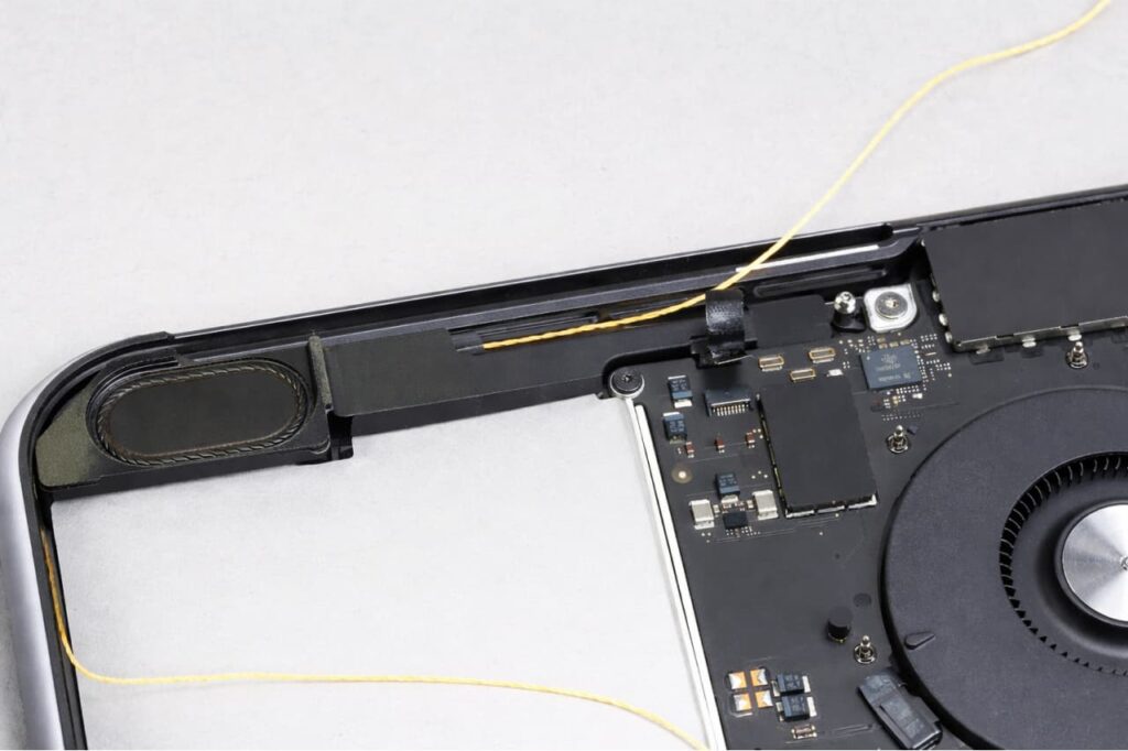 Haut-parleur interne d'un MacBook Air ouvert visible à côté de la carte mère et du ventilateur — remplacement haut-parleur MacBook qui grésille