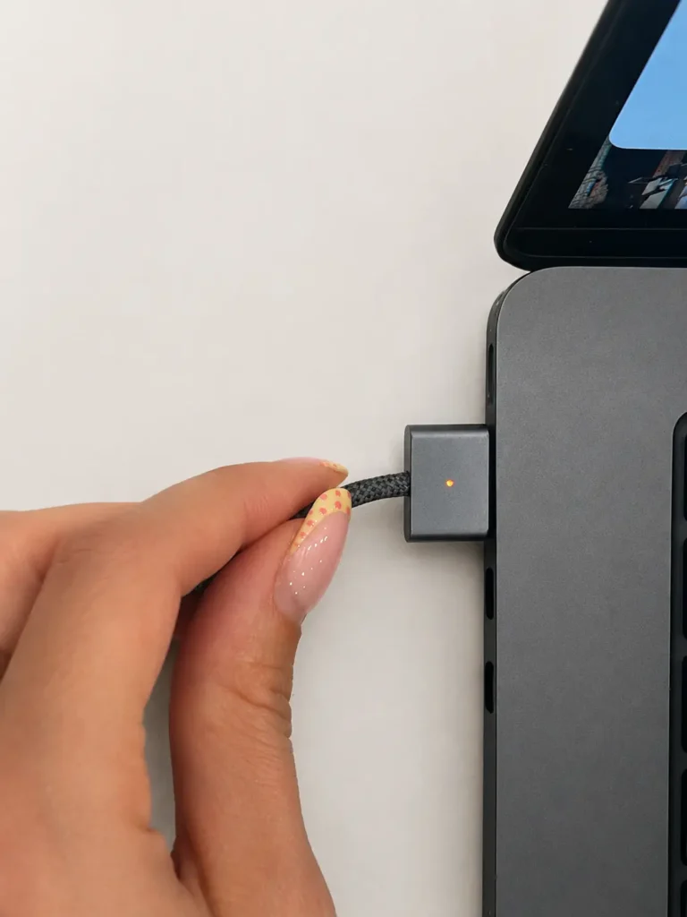Utilisatrice retirant le connecteur de charge MagSafe d’un MacBook Air Apple.