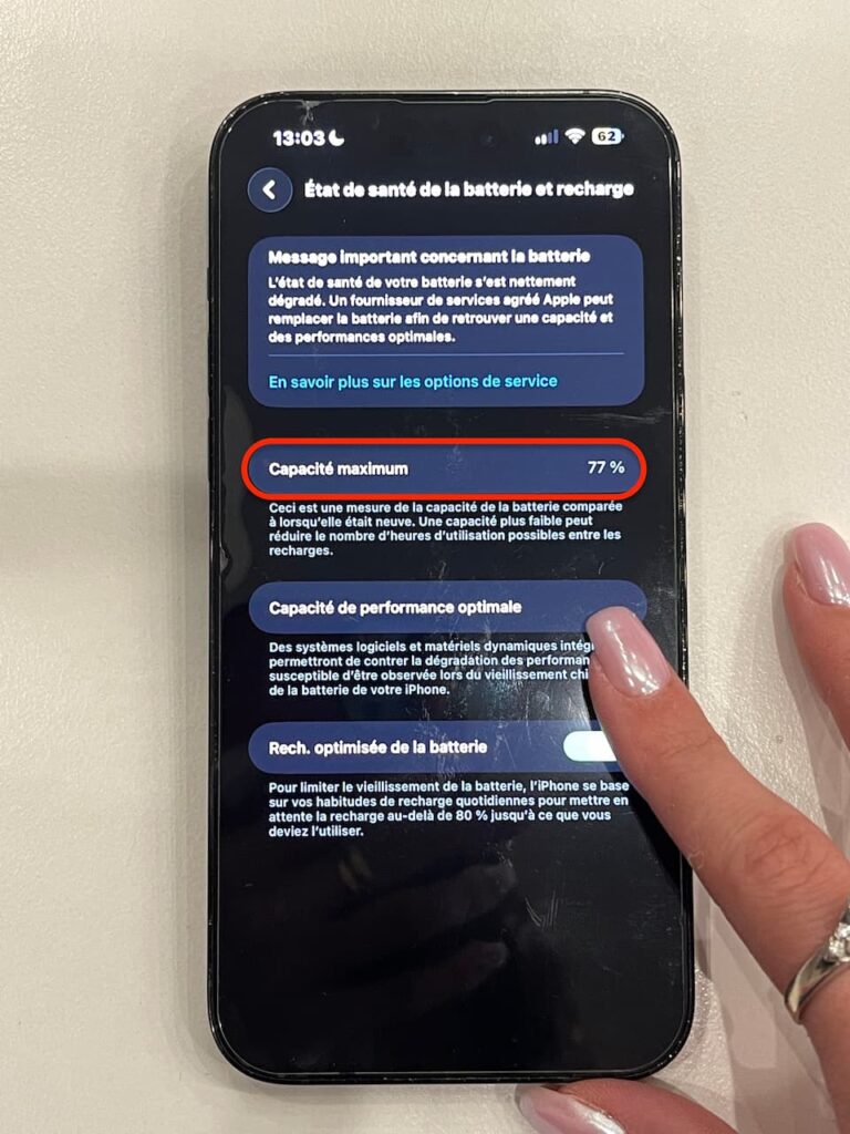 Écran d’un iPhone affichant une capacité maximale de batterie de 77 % et un message de réparation